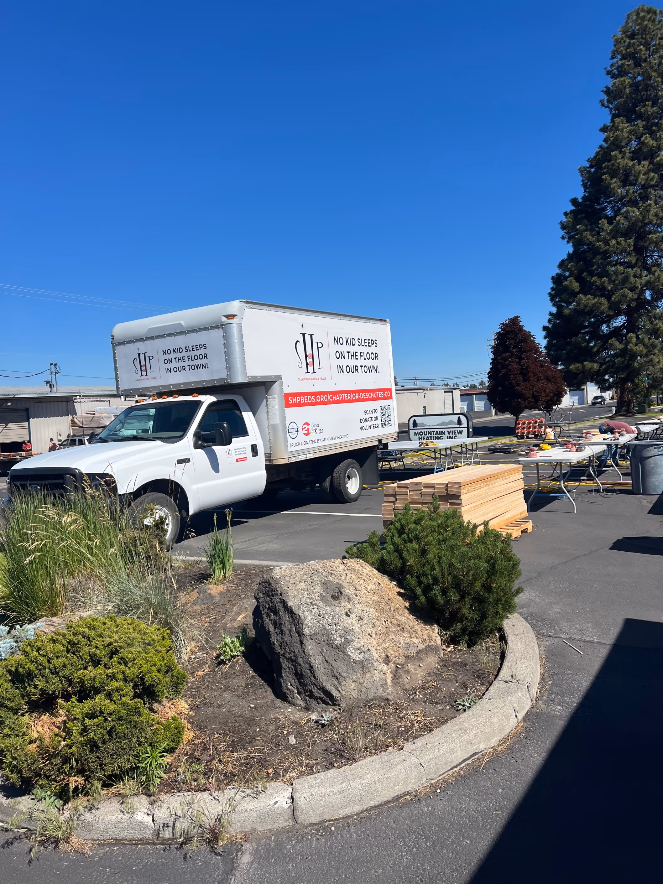 A box truck promotes the "No Kid Sleeps on the Floor" initiative in a community parking lot.
