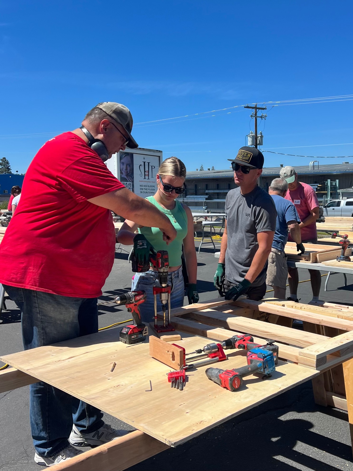 Participants learn woodworking skills at a community workshop, using drills and hand tools.
