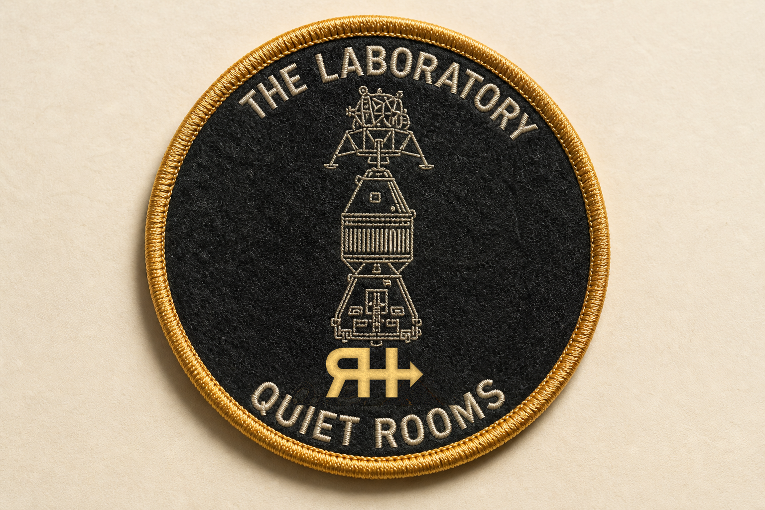 Gold merrow Laboratory patch: SLA stack in cream line, THE LABORATORY, QUIET ROOMS, official RateHighway mark at six o'clock.