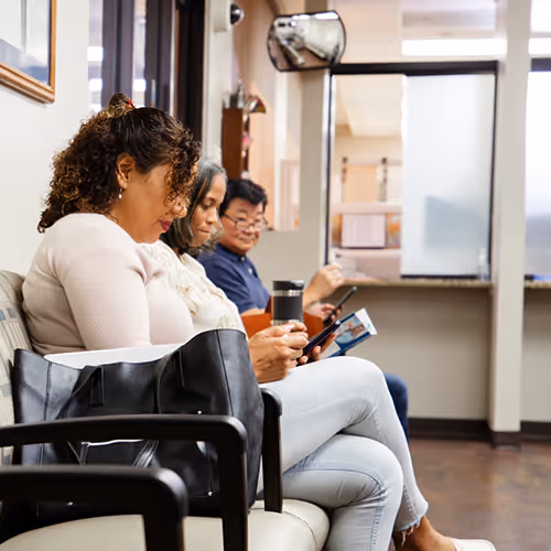 Several people wait in a clinic waiting room.