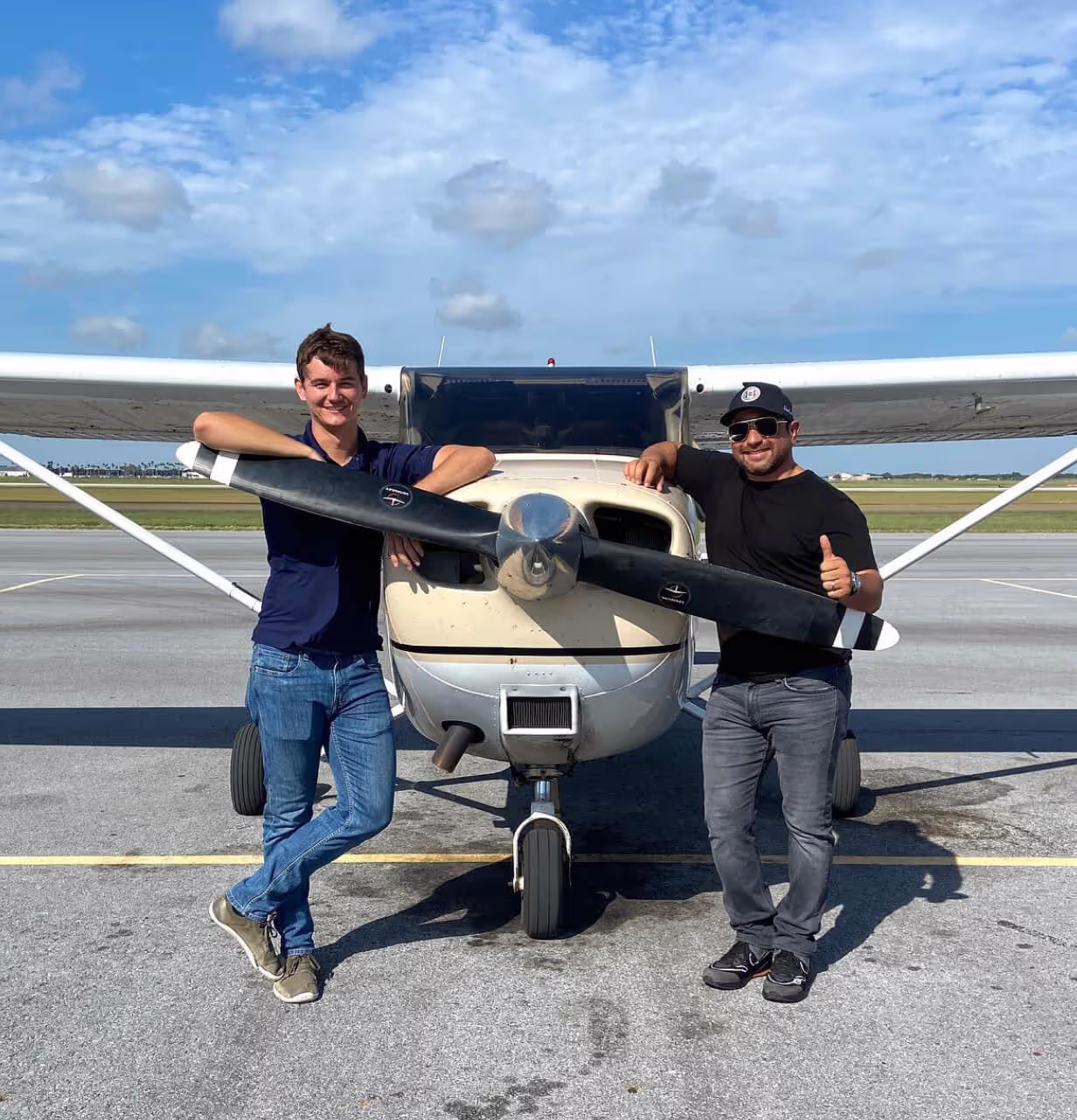 Flight school student and instructor standing in front of plane.