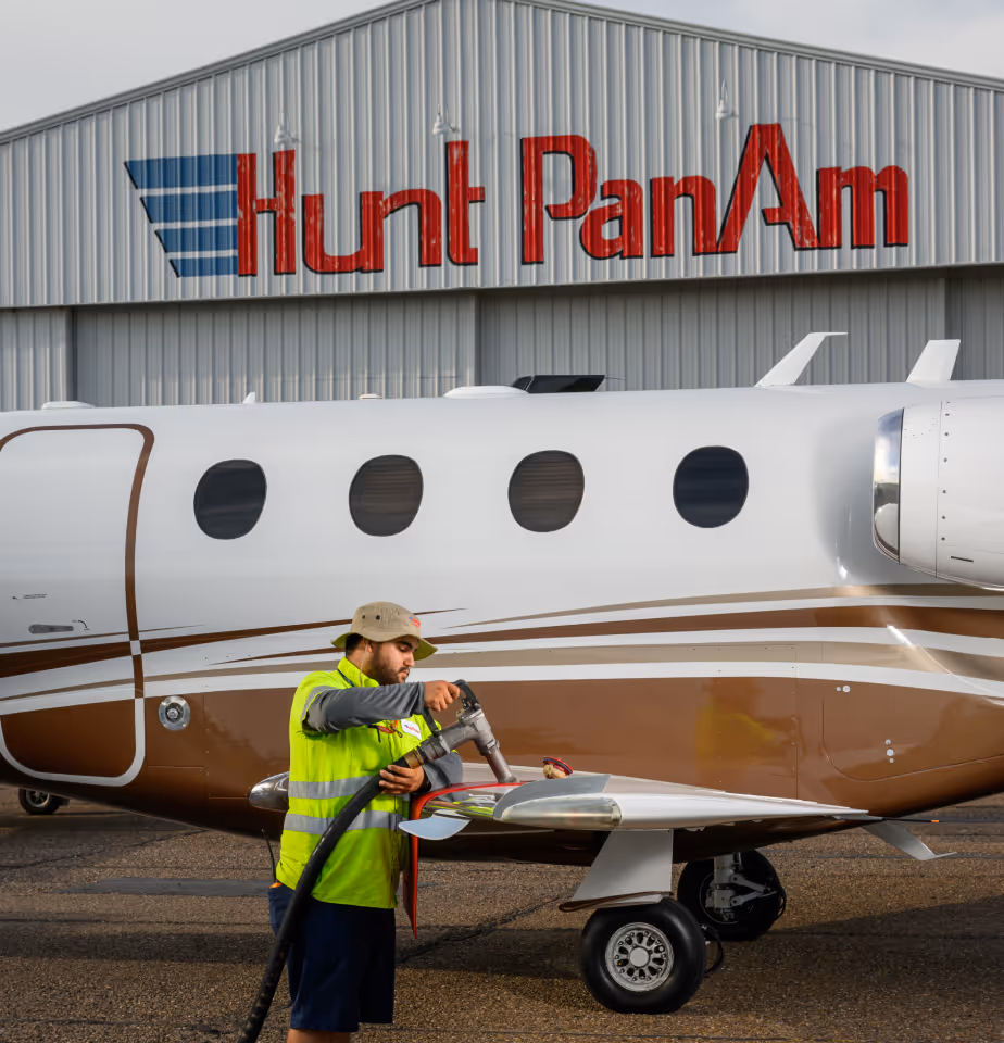 Employee fueling aircraft with Hunt PanAm hangar in background.