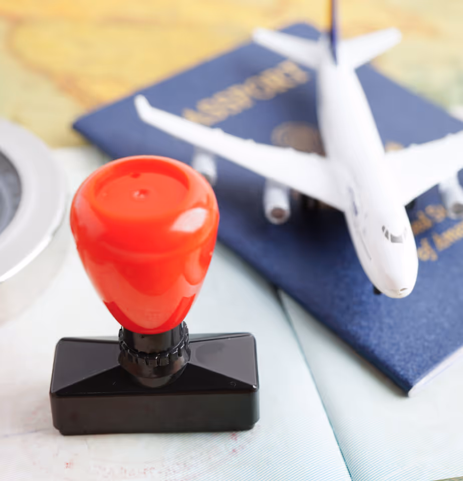 Passport stamp with passport and miniature plane in the background.