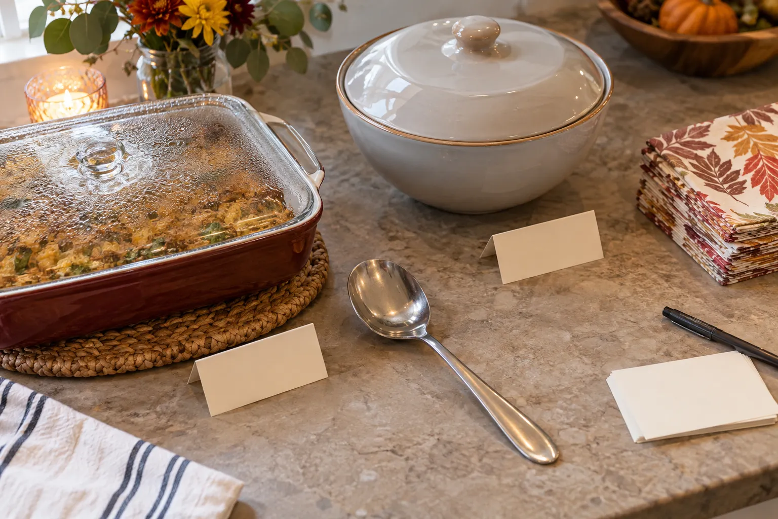 Covered potluck dishes on a clear kitchen receiving surface with blank cards ready for contribution details.