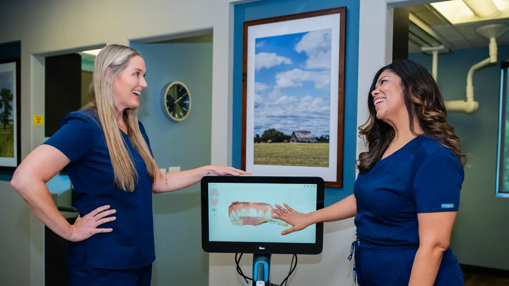 Dental office with dark cabinets, countertops, and a glimpse into a treatment room with dental chair.