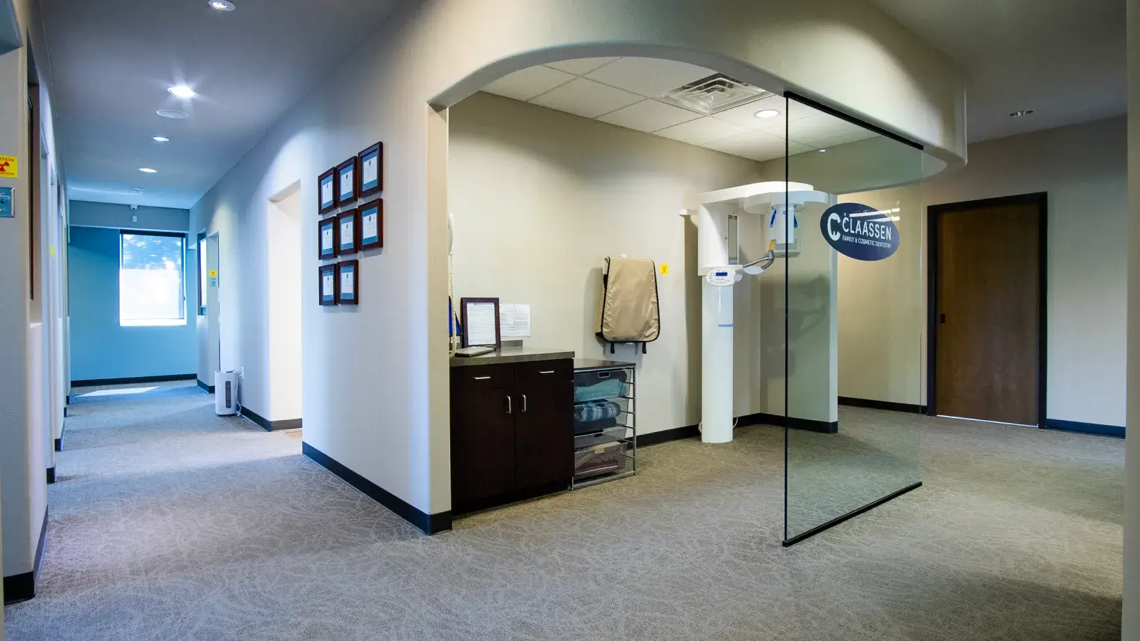 A digital screen displays a 3D image of human teeth in a dental office hallway.