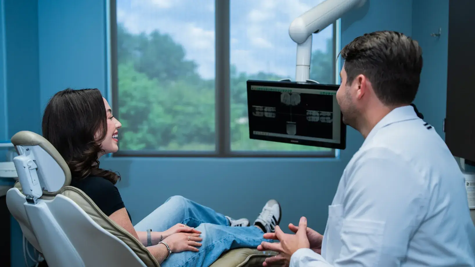A dental office features a panoramic X-ray machine near a doorway leading to a treatment room.