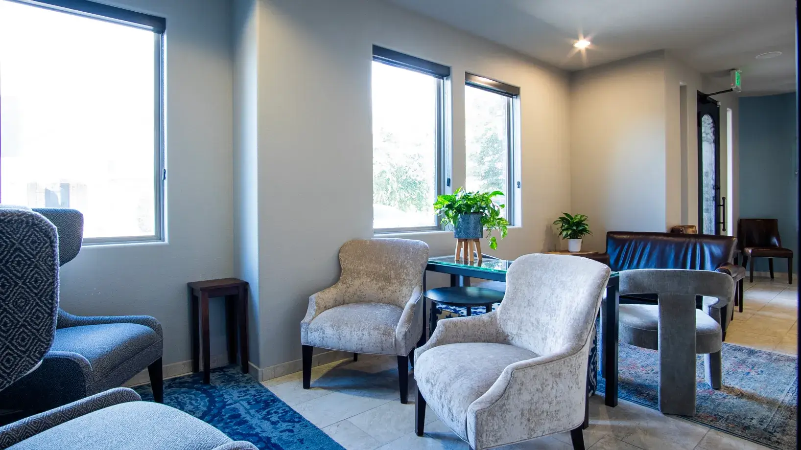 A modern waiting area with chairs, a round table, wall art, and a television.
