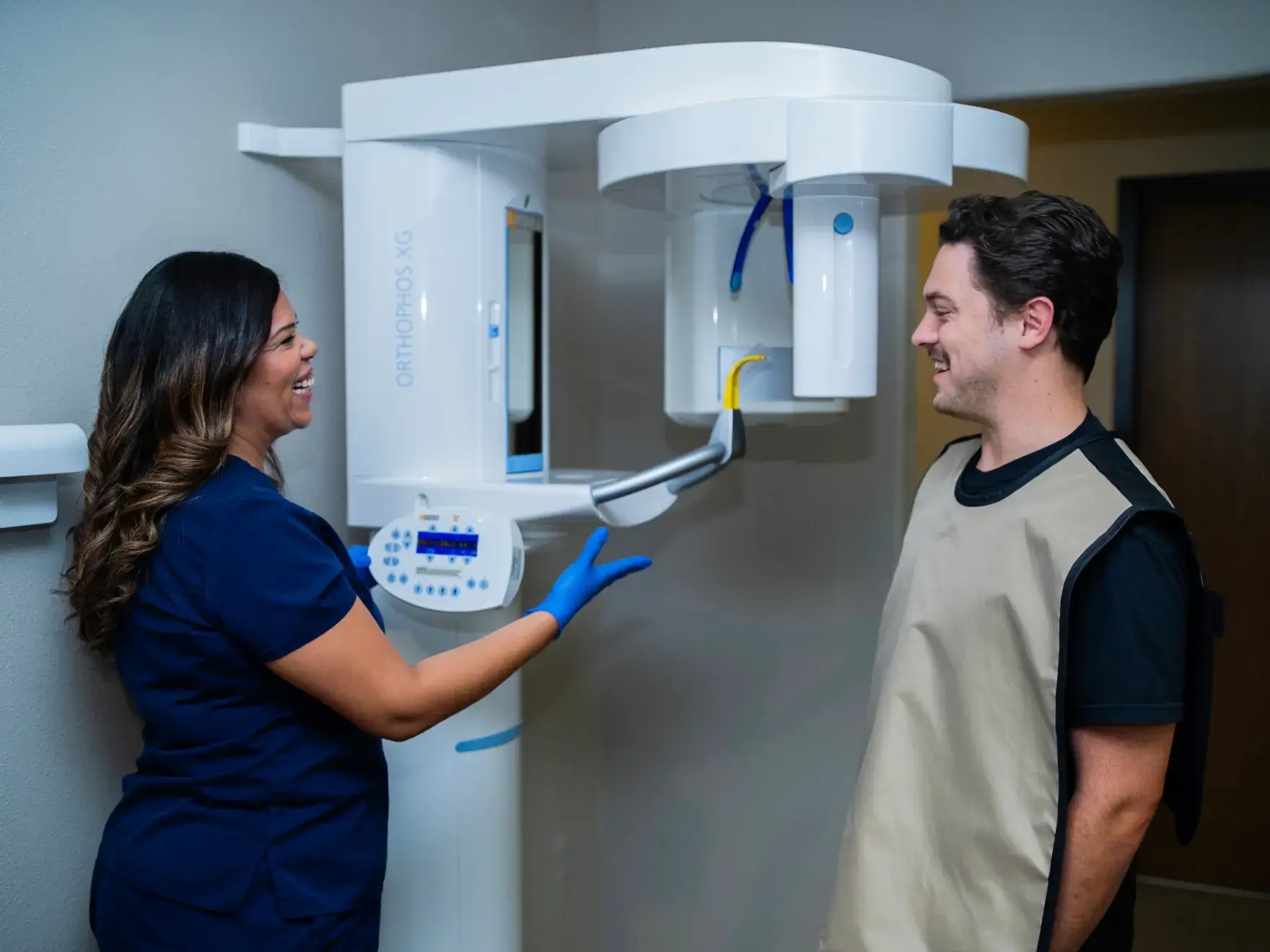 A dental professional is preparing a patient for a dental X-ray using specialized equipment.