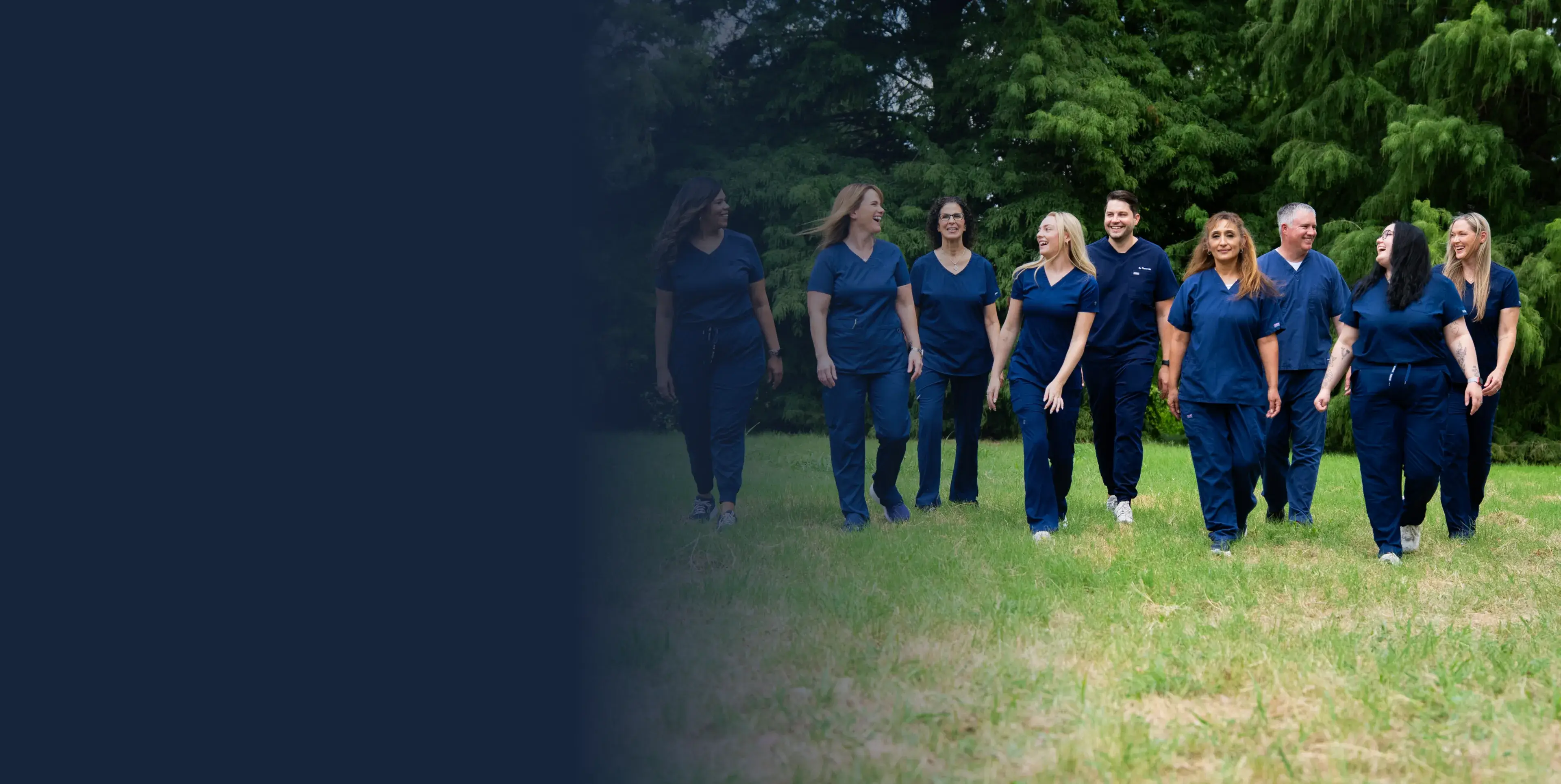 A group of people in blue scrubs walking together on grass.