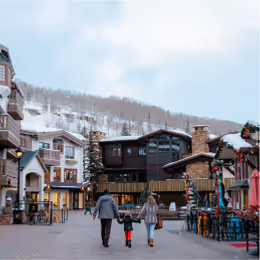 A family at a ski resort walking towards a building.