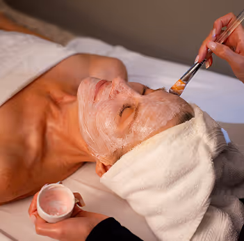 A women getting a facial with her hair wrapped in a towel.