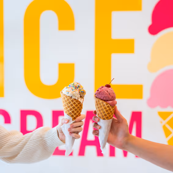 A close up of two hands holding ice cream cones.