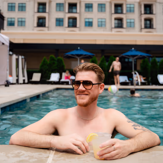 A man in a pool holding a cocktail.