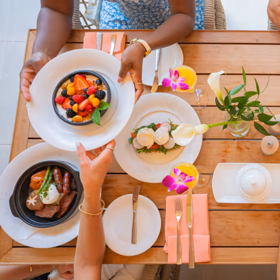 Overhead shot of food on a table with hands holding one of the plates.