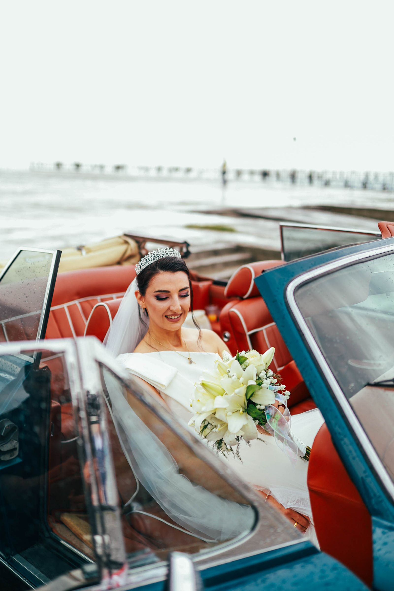 Bride in wedding dress sitting in a classic convertible car