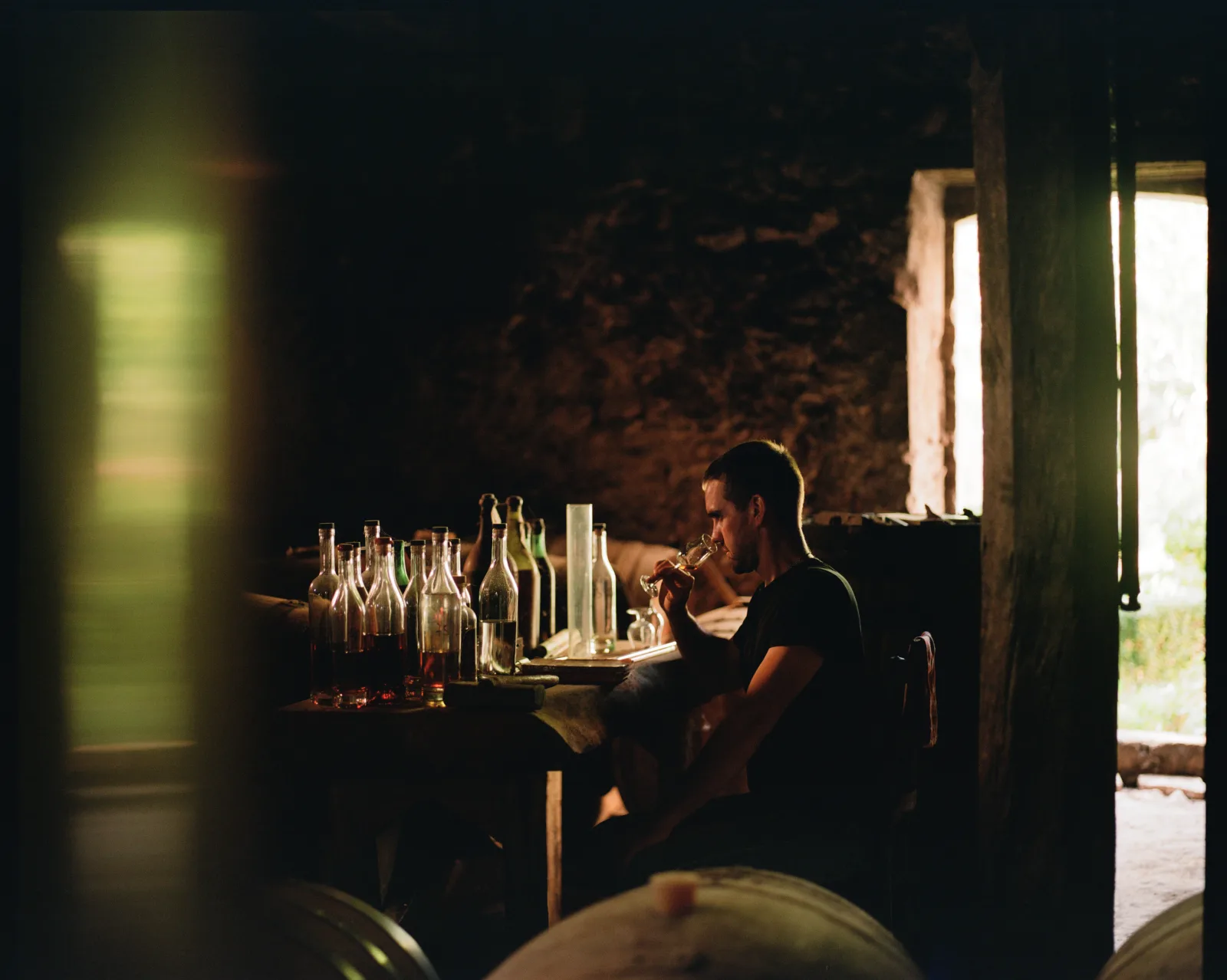 Tasting Armagnac beside sample bottles in the stone cellar at Château Lassalle Baqué in Montréal-du-Gers, France.