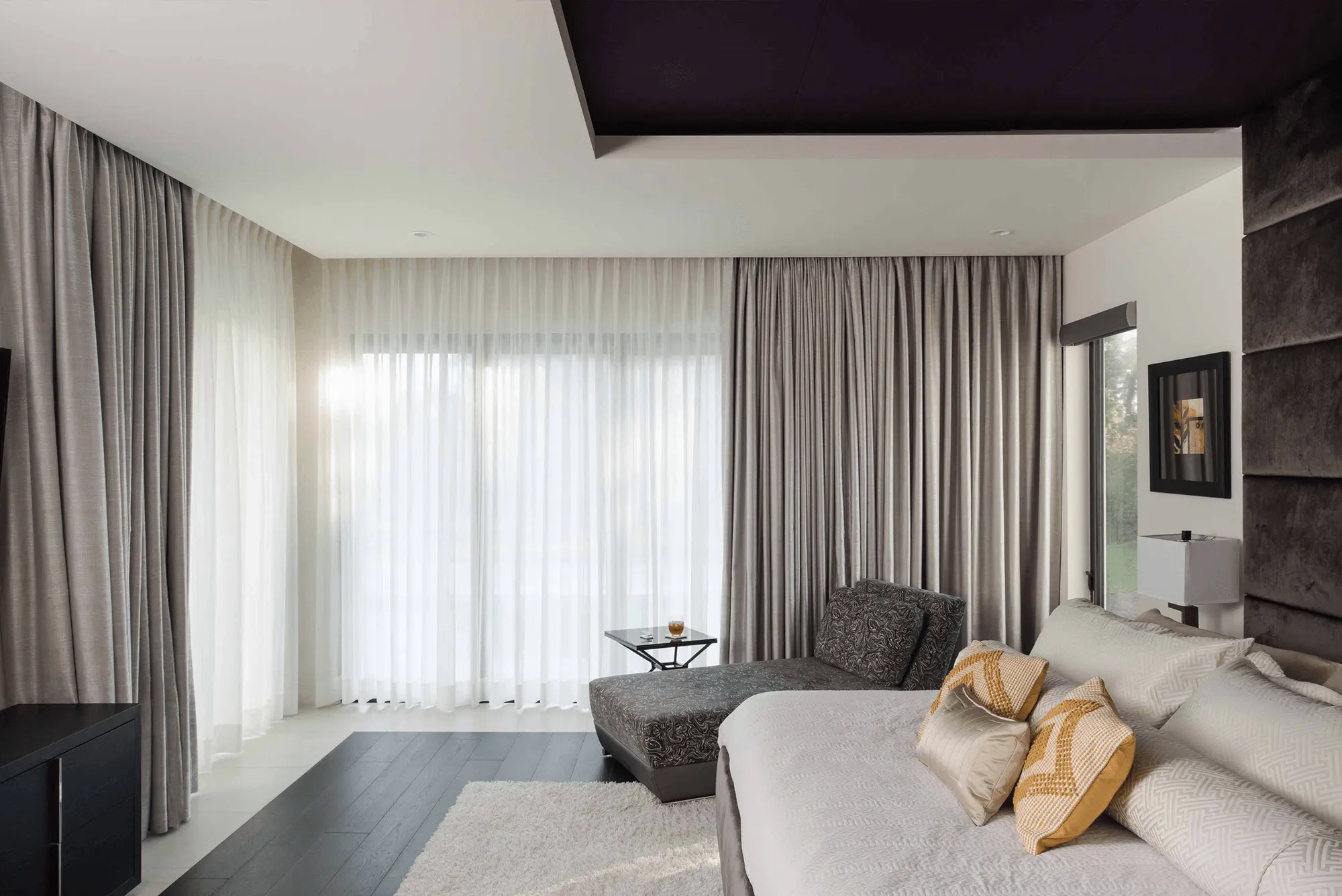 Bedroom with gray and white curtains, chaise lounge, and bed