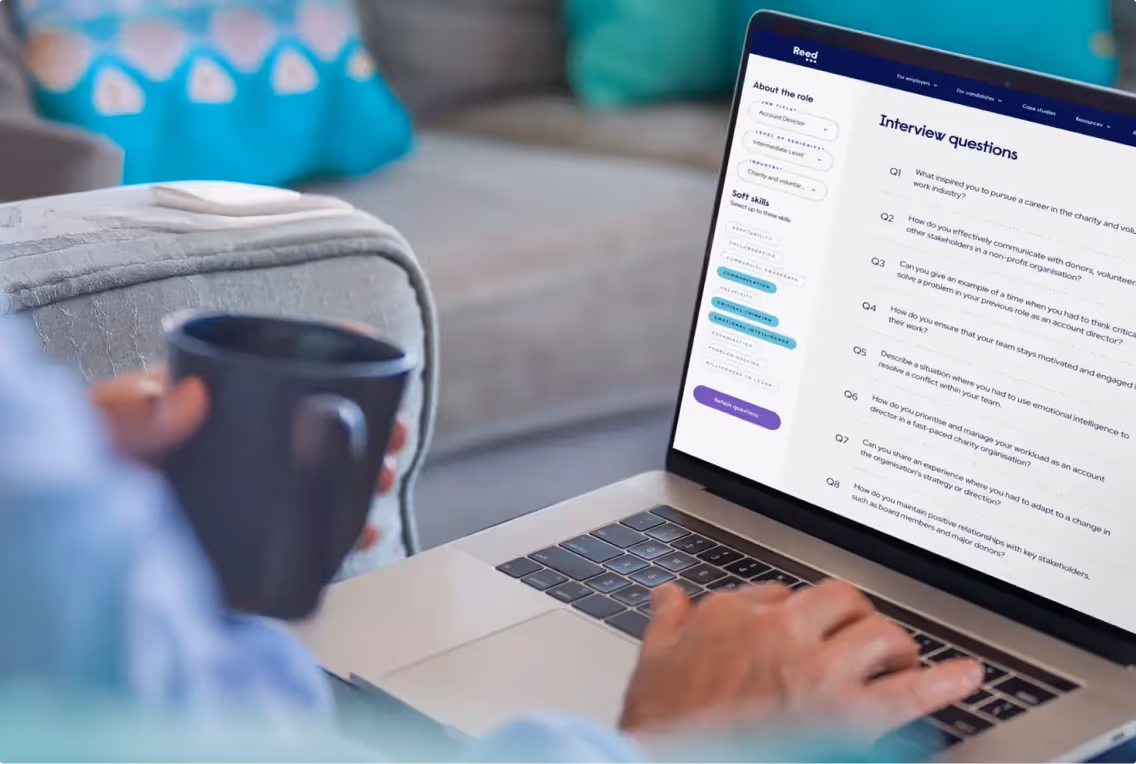 Person sitting on couch with coffee using reed on a laptop