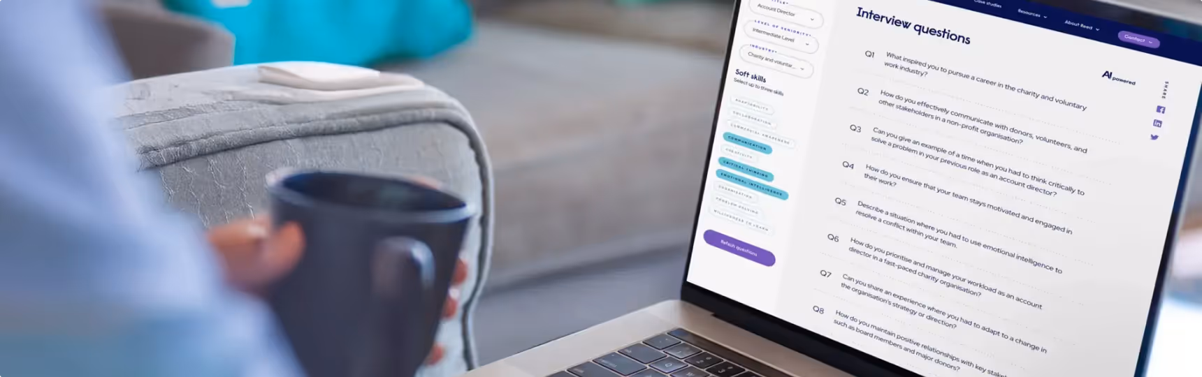 Person sitting on couch with coffee using reed on a laptop