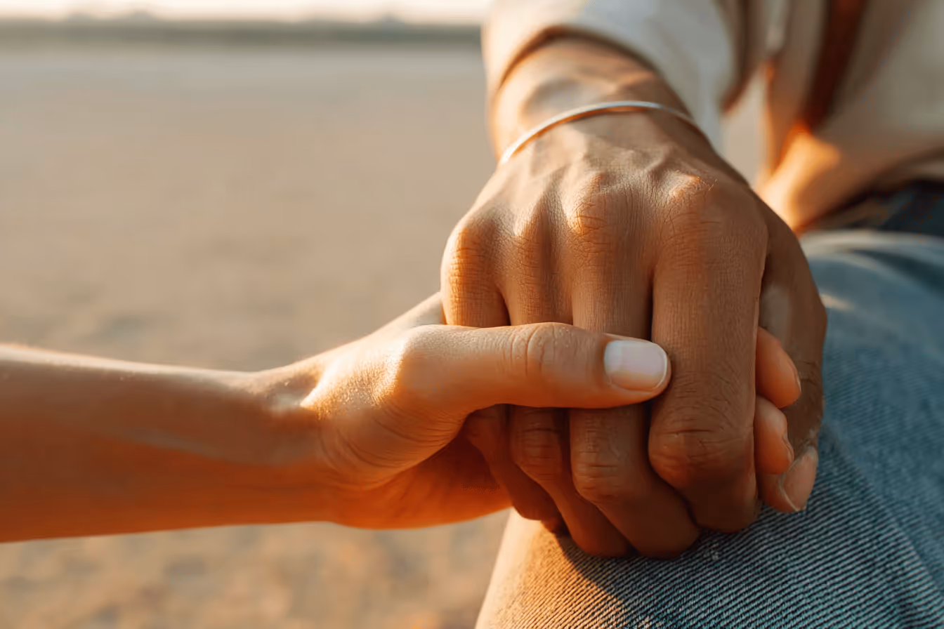 A person gently holds the hand of another, symbolizing support and connection between them.