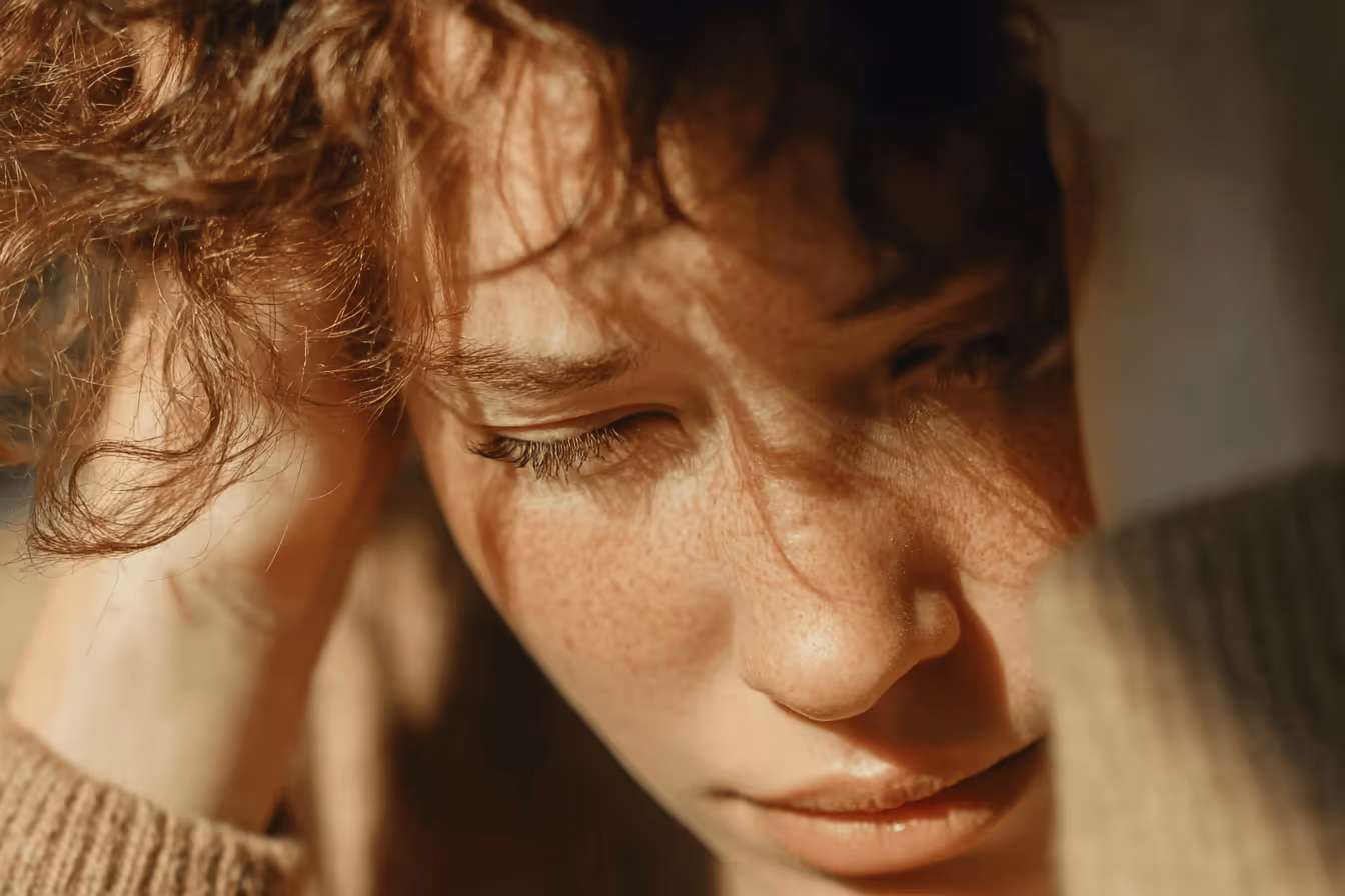 A woman sitting with her head in her hands, expressing distress or deep contemplation.