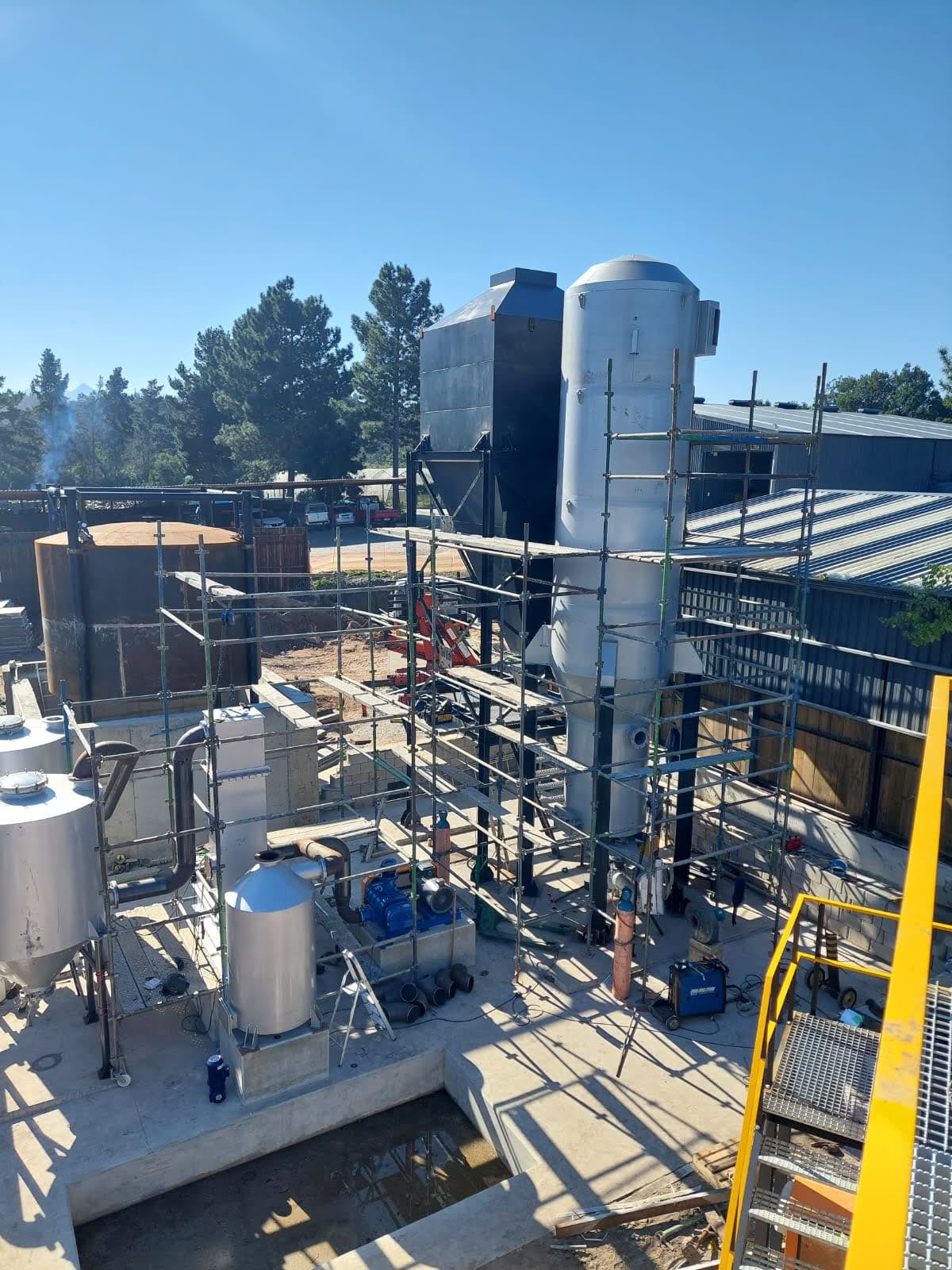 Syngas generation module under installation at a bioenergy site, showing vertical reactor units, scaffolding, and process vessels on concrete footings.