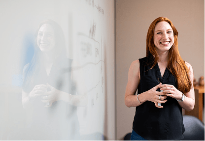 A smiling young adult in front of a classroom