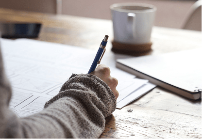 student studying with pen, paper and coffee on the table.