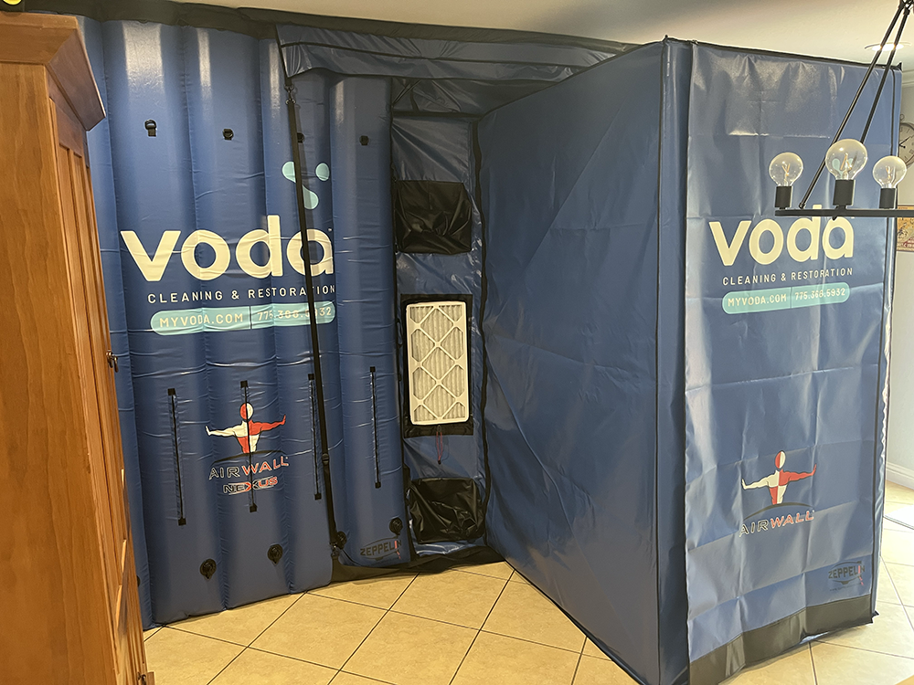 Blue Voda air purification tent with cleaning and restoration branding set up indoors on tiled floor.