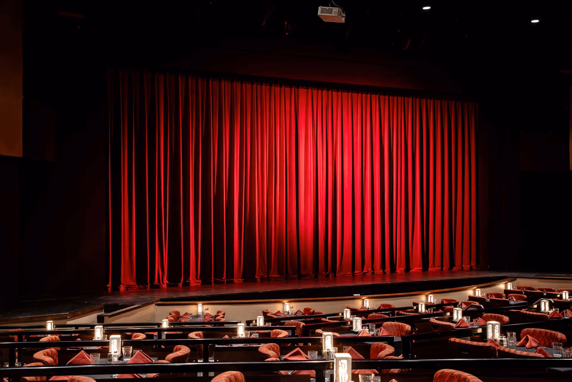 A wide shot of a theatre stage with a striking red curtain.