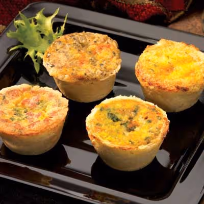 Four quiches displayed on a black plate.