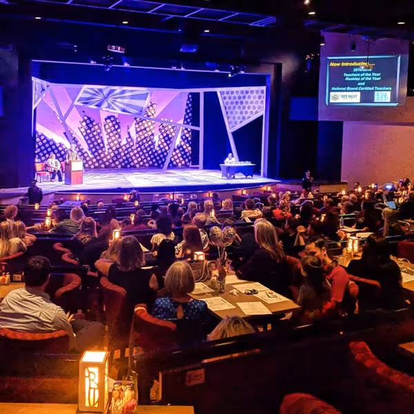 A theatre full of guests watches a performance attentively.