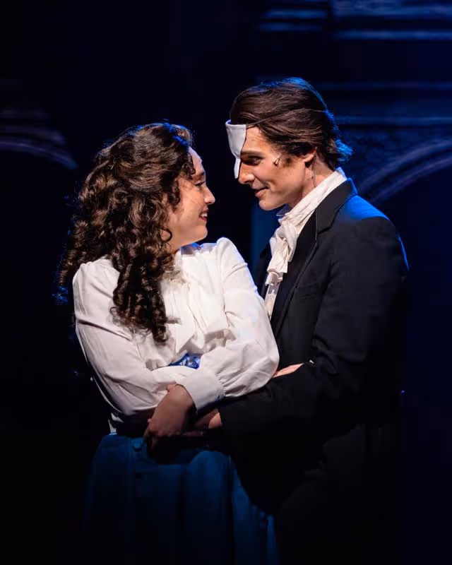 The lead actors of Phantom of the Opera looking into each others eyes.