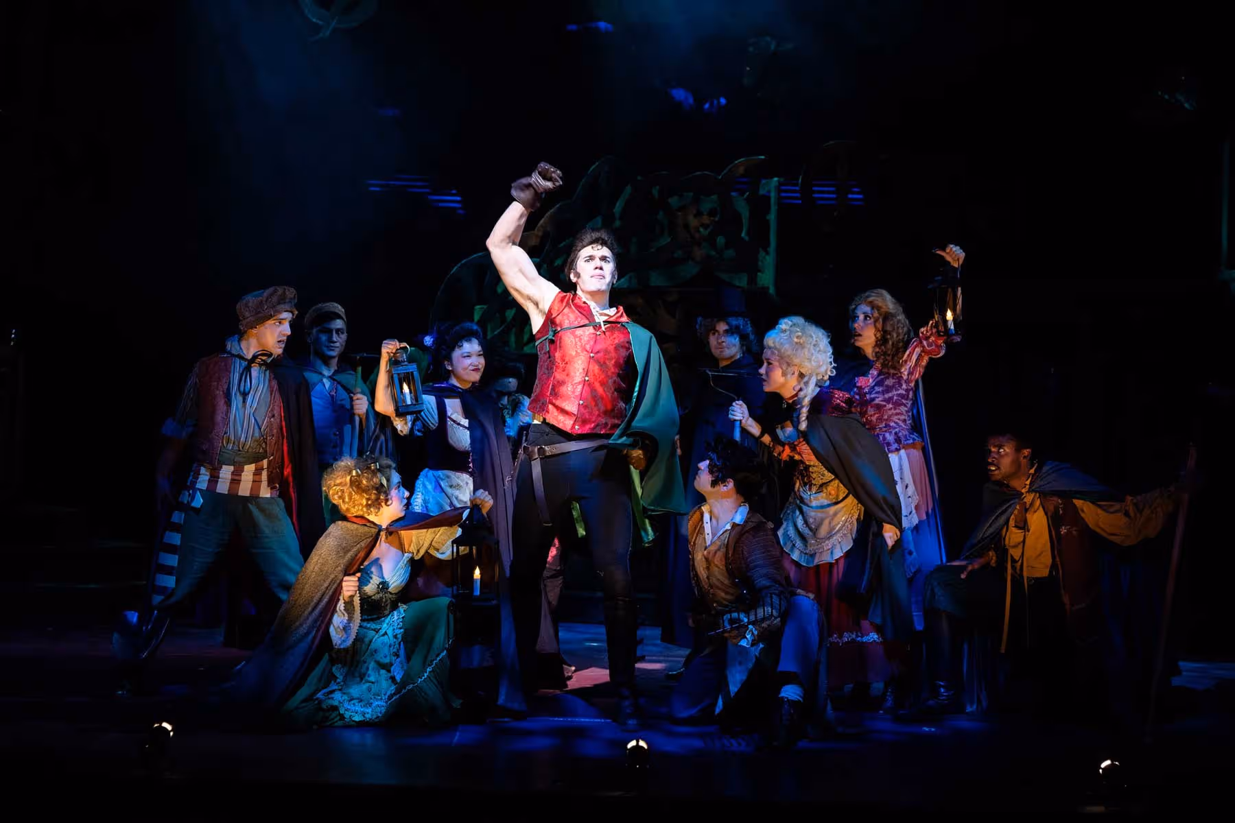 An actor portraying the character of Gaston from "Beauty and the Beast" holds his fist up triumphantly.