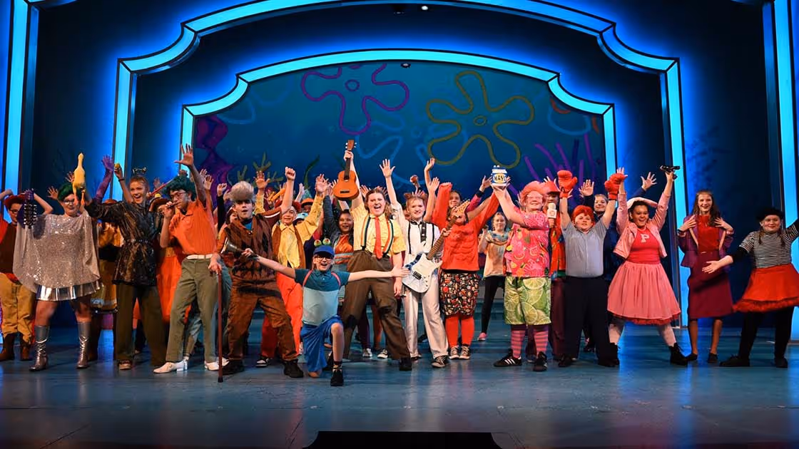 A group of child actors pose on stage after performing in Spongebob The Musical.