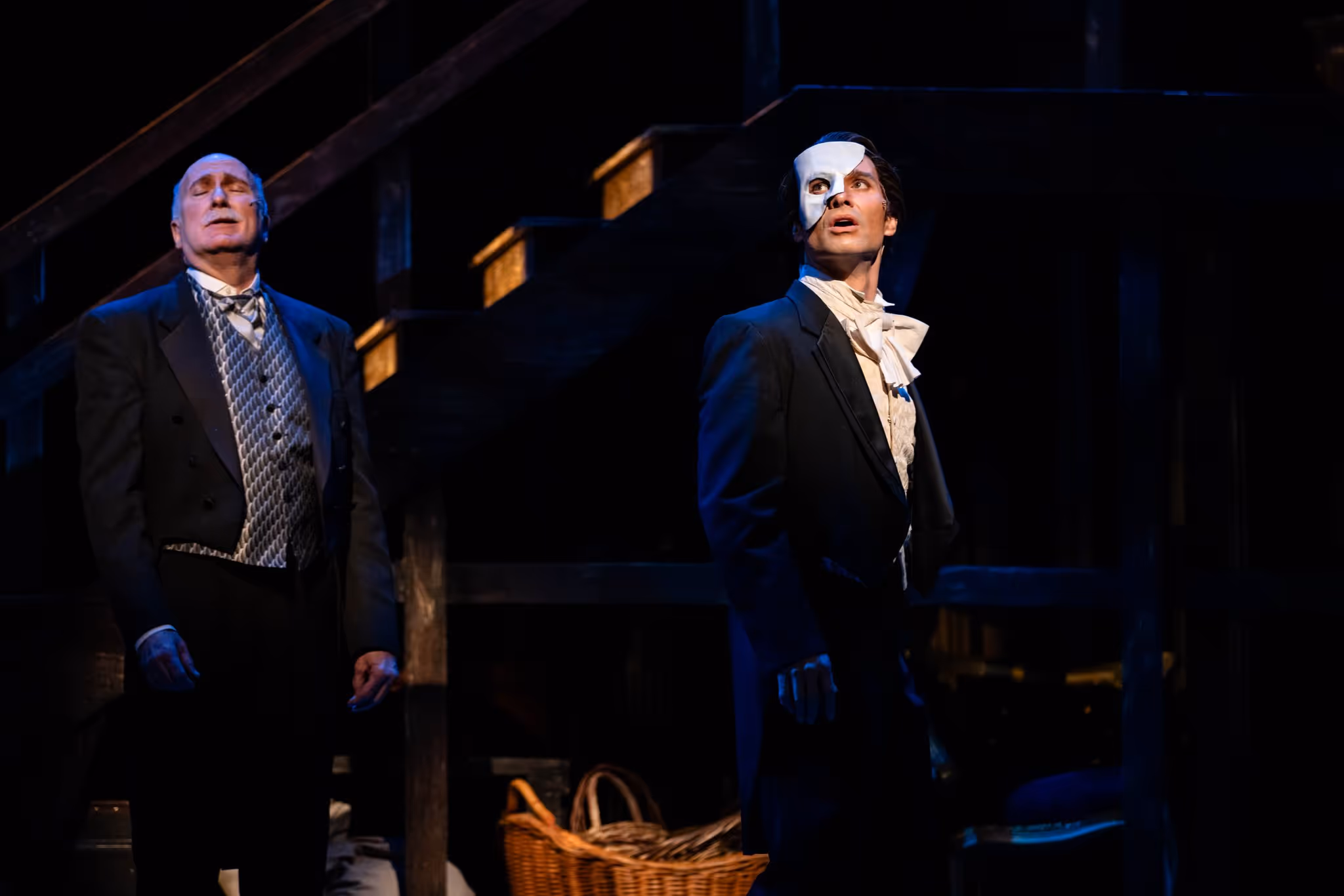 A man wearing a partial mask over his face acts in the Broadway musical Phantom of the Opera.