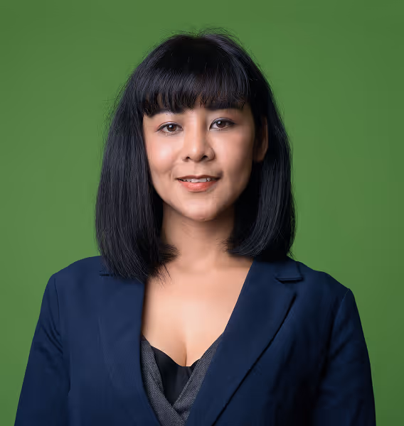 Portrait of a woman with straight black hair and bangs wearing a navy blazer against a green background.