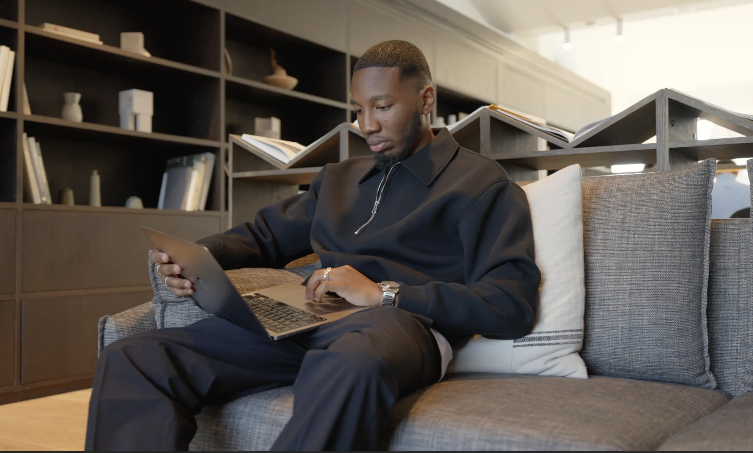 A man sat on a sofa in an office using a laptop
