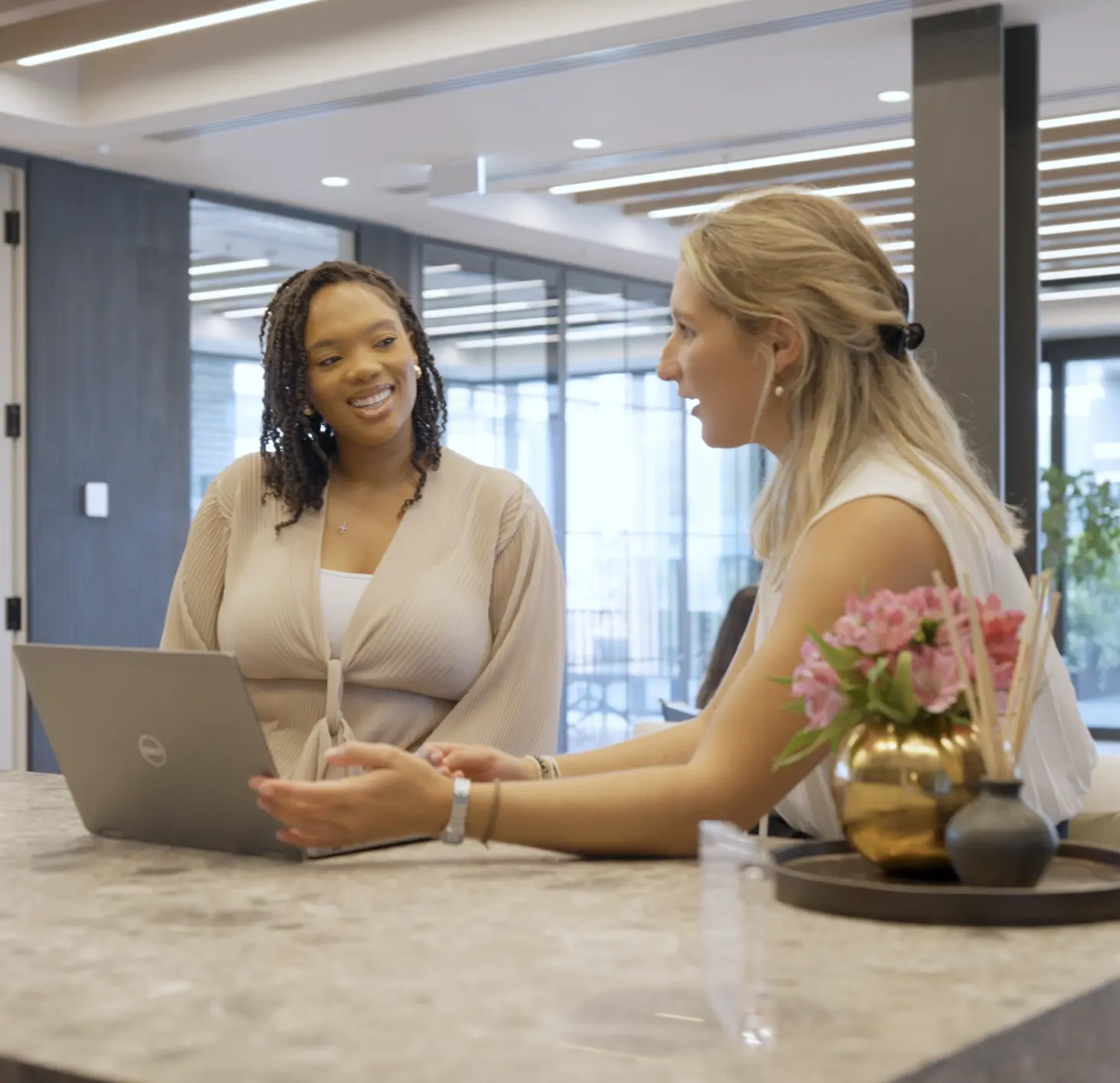 Two women in an office having a discussion in front of a laptop.
