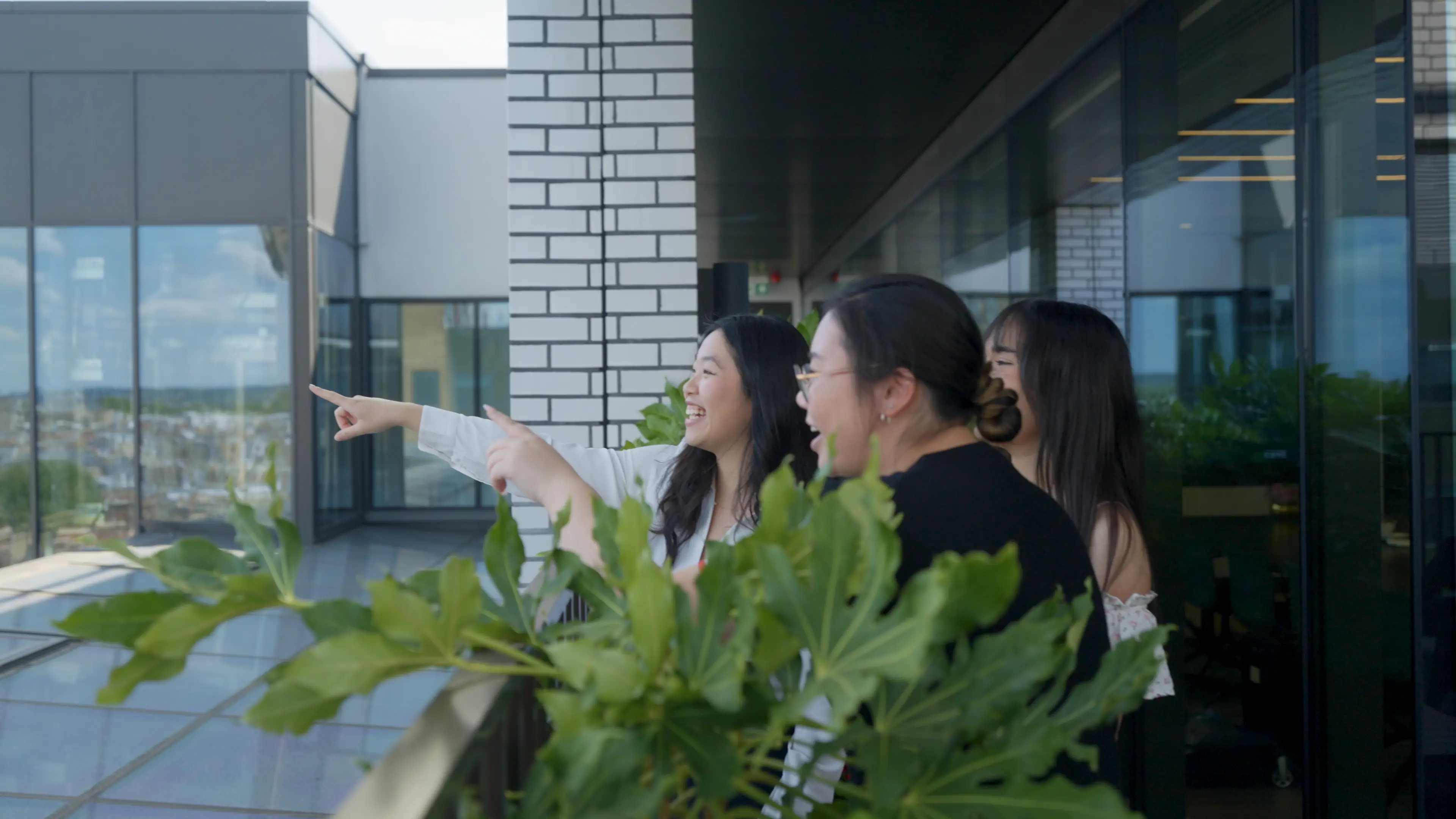 Group of friends smiling and pointing while standing on a balcony.
