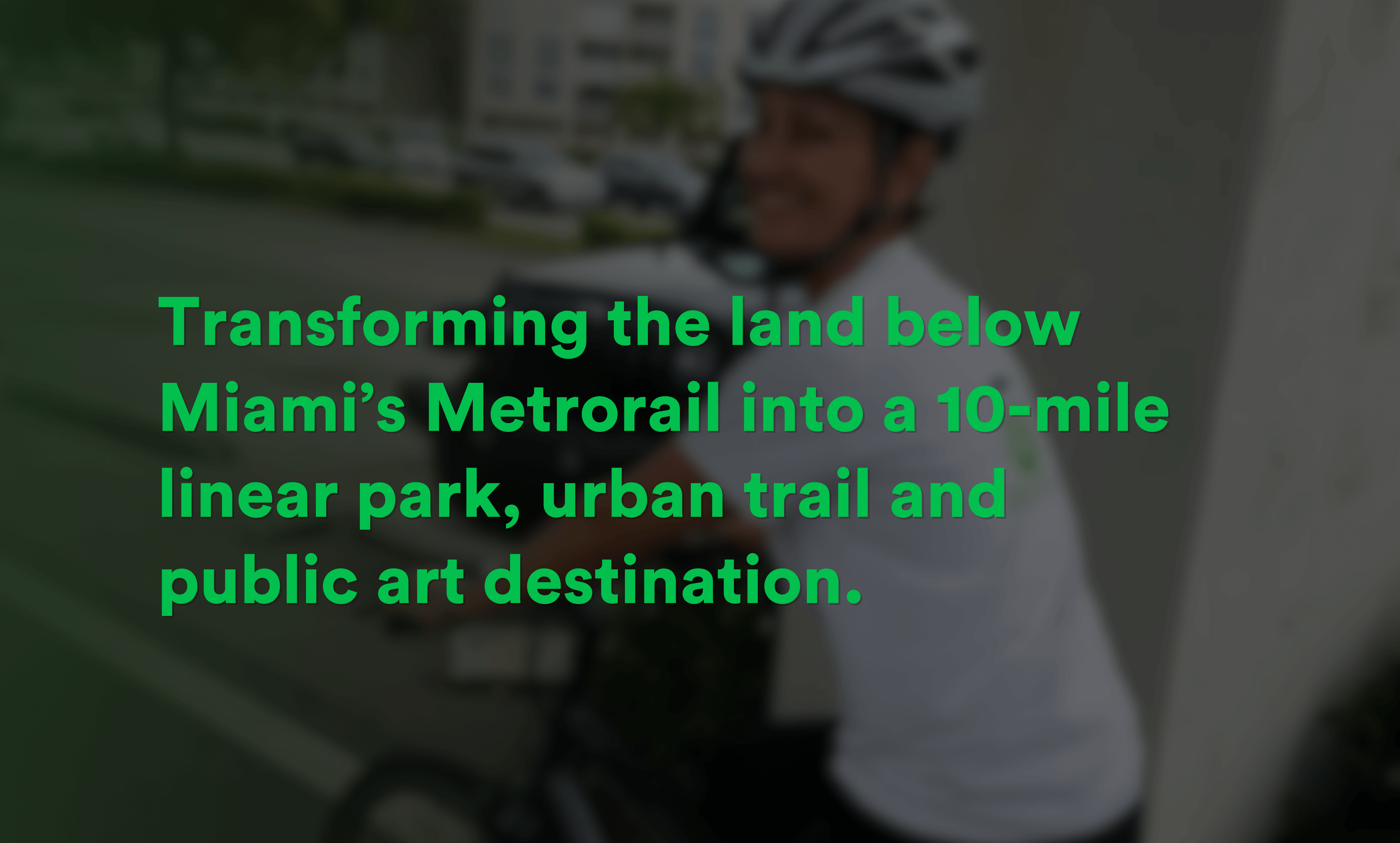 Smiling person wearing a bicycle helmet sitting on a bike with the text overlay about transforming land below Miami’s Metrorail into a 10-mile linear park, urban trail, and public art destination.