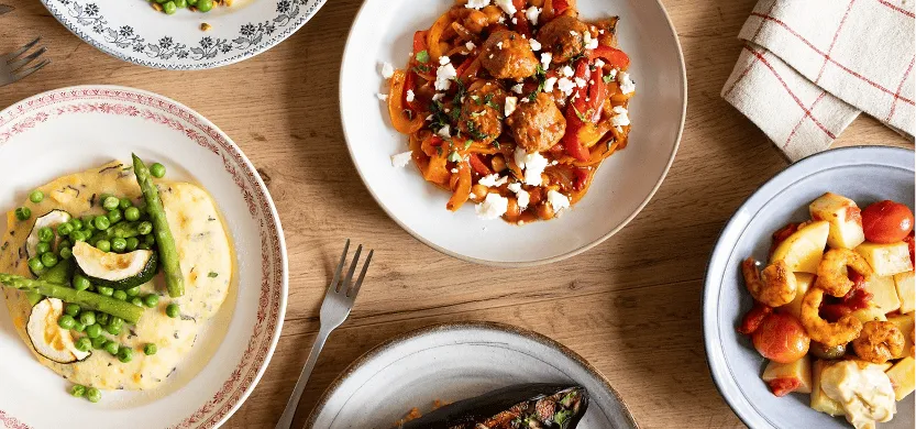 Table dressée avec différents plats cuisinés par Popchef : purée avec des légumes verts, boulettes de viande sur des légumes marinés, salade de crevettes, aubergines grillés au four
