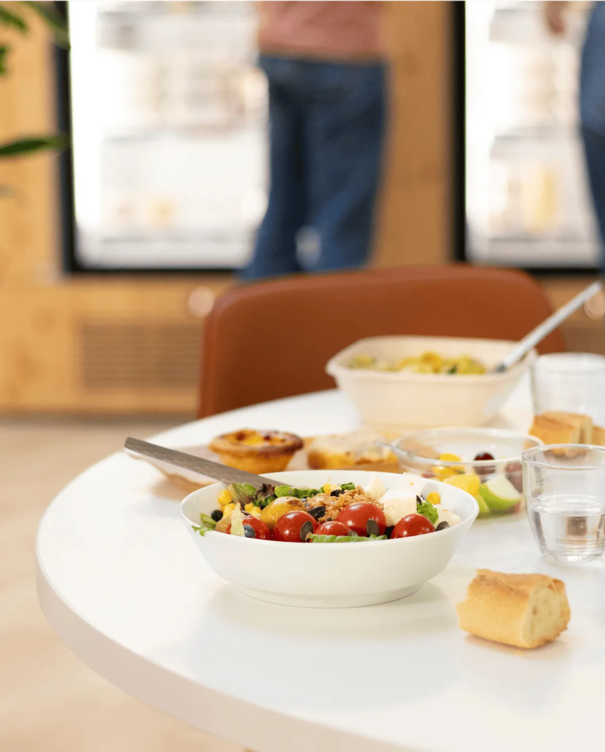 une table dressée avec une salade composée, du pain, des fruits et des pâtisseries en dessert