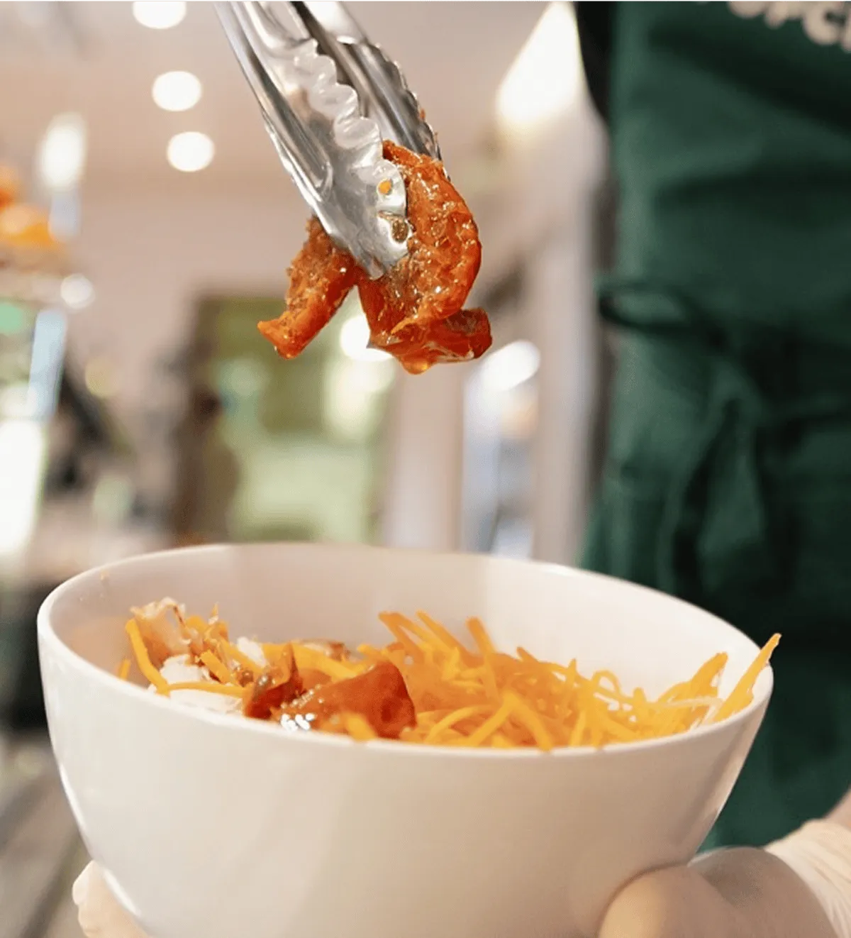 une personne ajoute des tomates séchées dans le plat qu'elle prépare