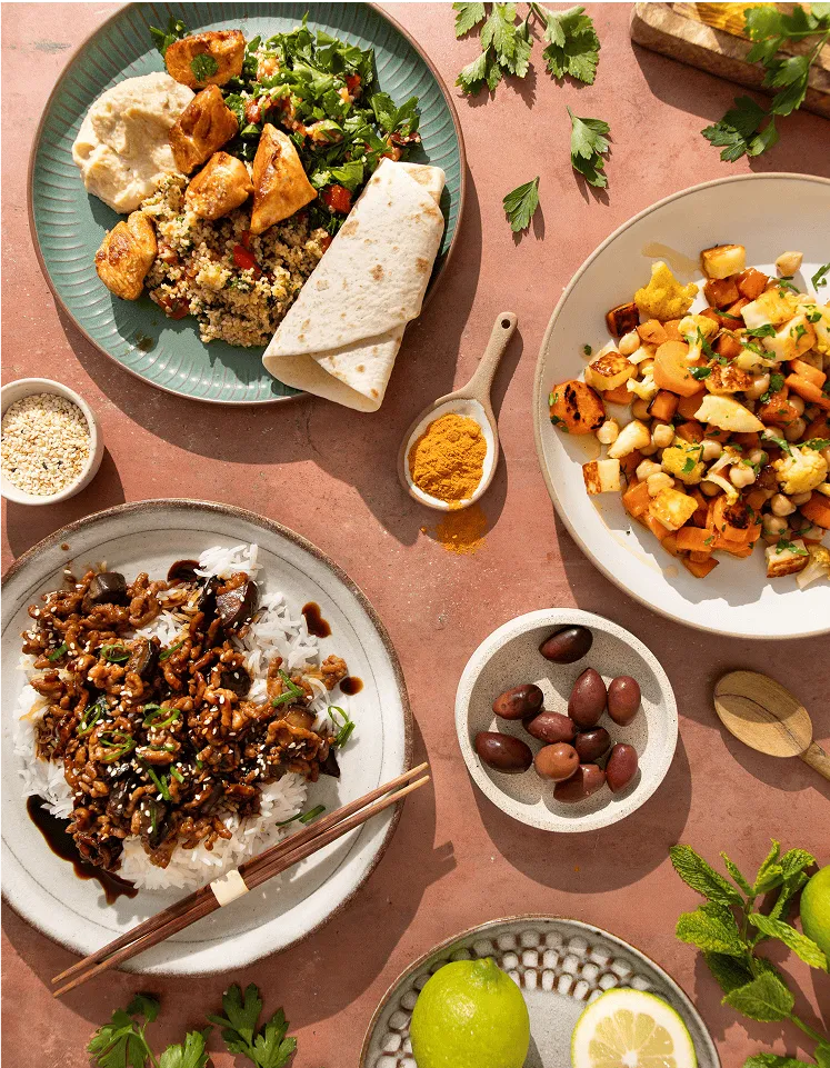 Table dressée avec différents plats cuisinés par Popchef : taboulé et salade composée accompagnés d'un wrap, riz au boeuf façon asiatique, salade de légumes rotis