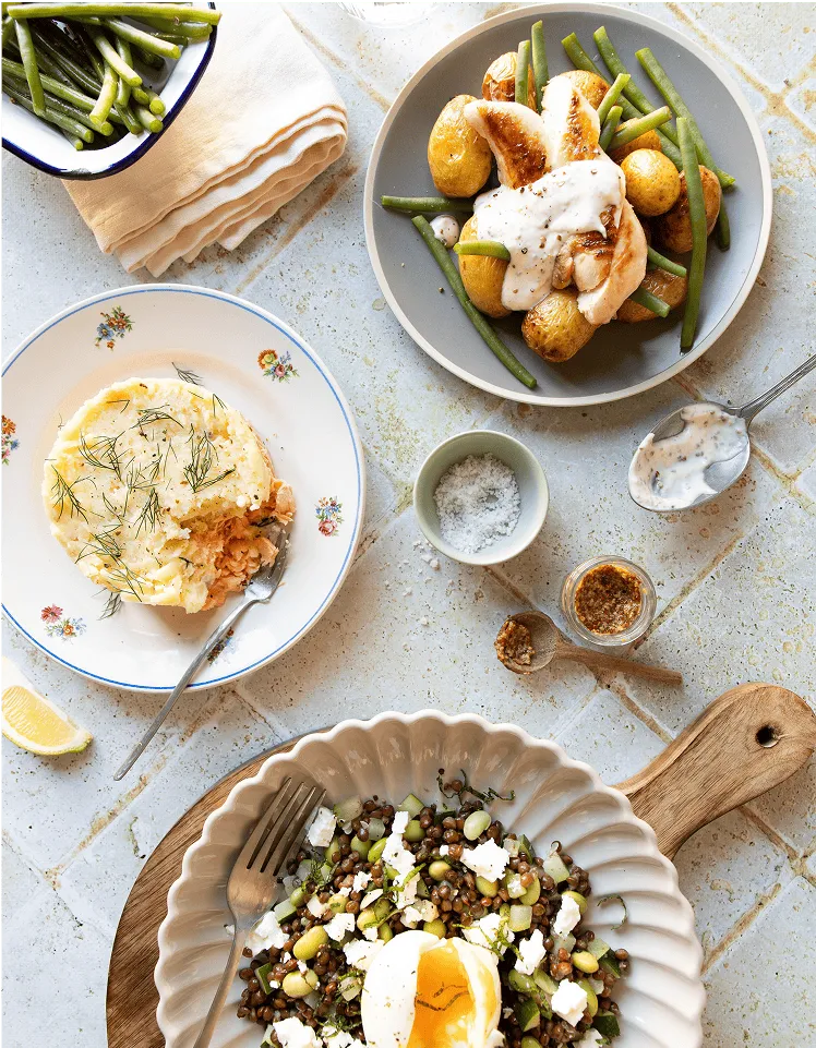 Table dressé de plusieurs plats : des haricots verts, une salade de lentilles, de la purée avec du saumon préparés par Popchef