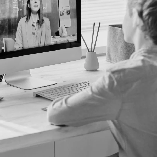 Black and white photo of a person attending an online therapy session on a computer.