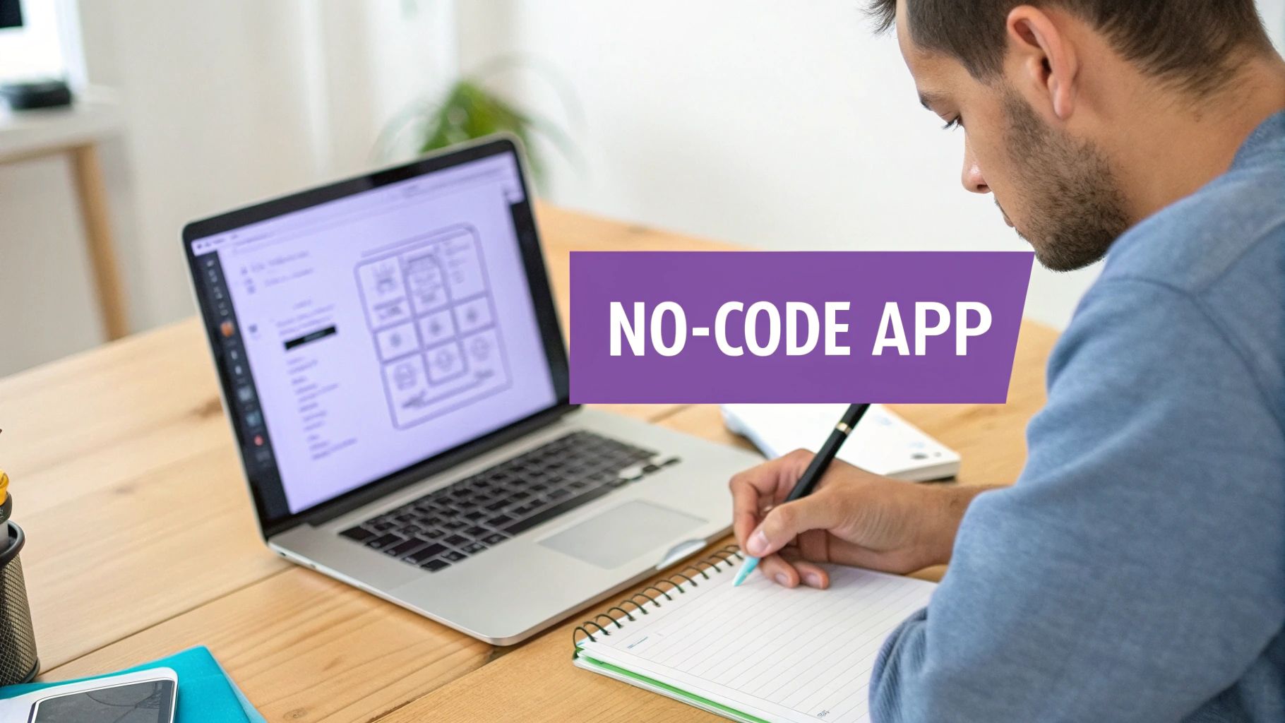 A man working on a laptop displaying a 'NO-CODE APP' interface, while writing in a notebook.