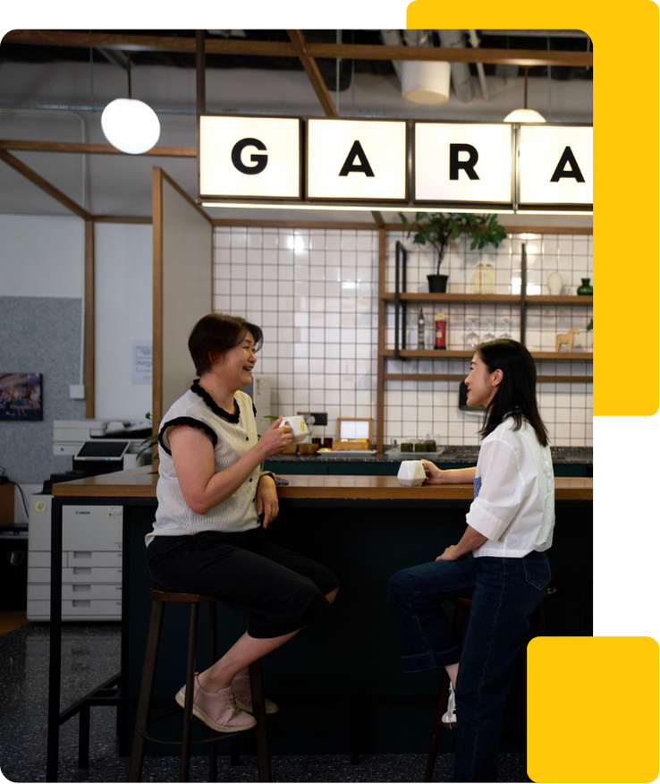 Two female colleagues having a coffee in a coworkspace pantry